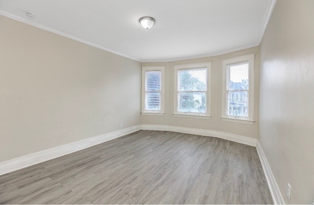 empty room with crown molding, a wealth of natural light, and light hardwood / wood-style flooring