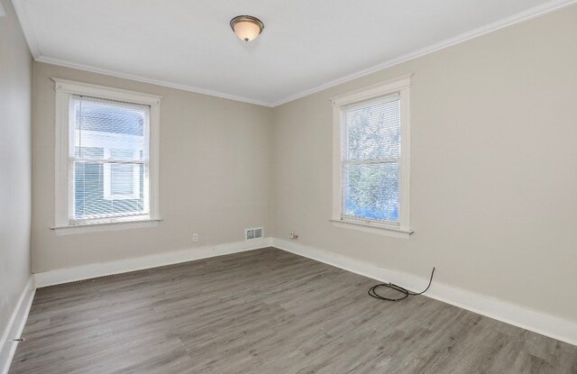 unfurnished room featuring wood-type flooring, crown molding, and a wealth of natural light