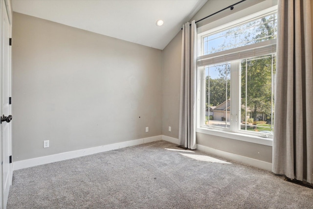 carpeted spare room featuring vaulted ceiling