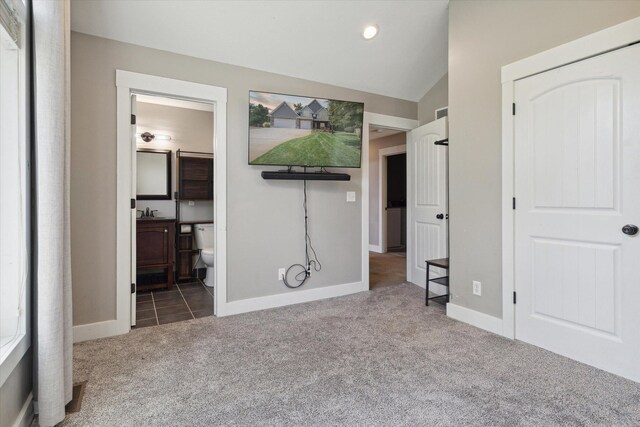 unfurnished bedroom with carpet, connected bathroom, and vaulted ceiling