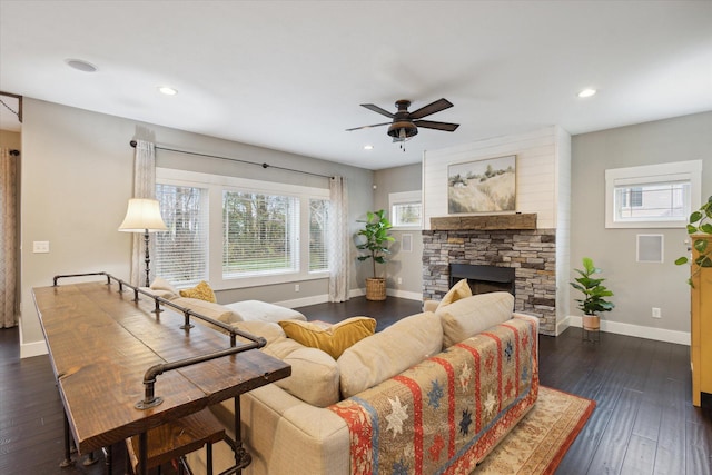 living room featuring dark hardwood / wood-style flooring, a stone fireplace, and ceiling fan