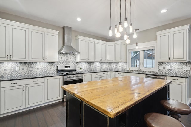 kitchen featuring stainless steel gas range oven, backsplash, wall chimney exhaust hood, dark hardwood / wood-style floors, and a kitchen island