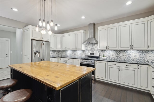 kitchen featuring wall chimney range hood, a kitchen island, dark hardwood / wood-style flooring, white cabinetry, and stainless steel appliances