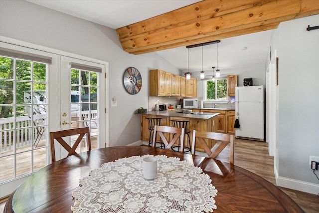 dining area featuring hardwood / wood-style floors and lofted ceiling with beams