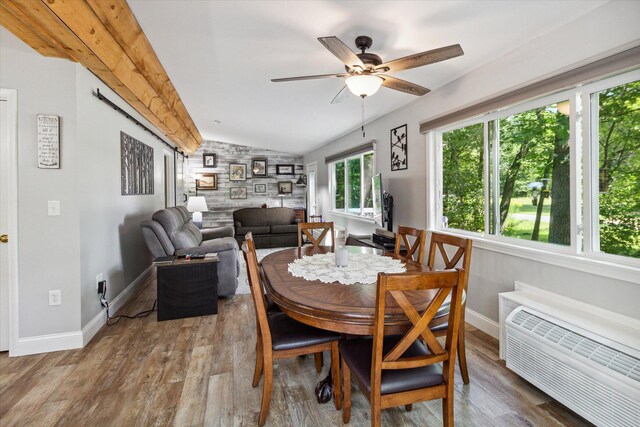 8529 N Blair Dr, Bitely, MI 49309 - dining space featuring vaulted ceiling, ceiling fan, baseboards, wood finished floors, and a wall unit AC