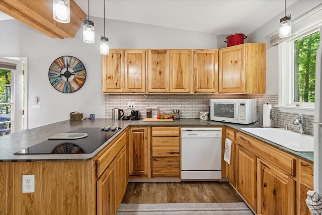 kitchen with kitchen peninsula, white appliances, vaulted ceiling, sink, and pendant lighting