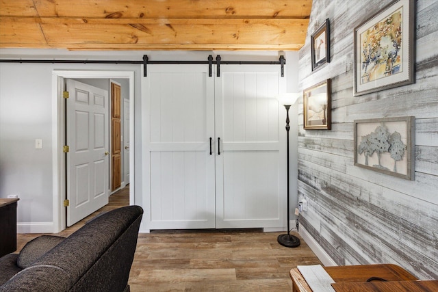 interior space featuring a barn door, hardwood / wood-style floors, beamed ceiling, and wooden ceiling