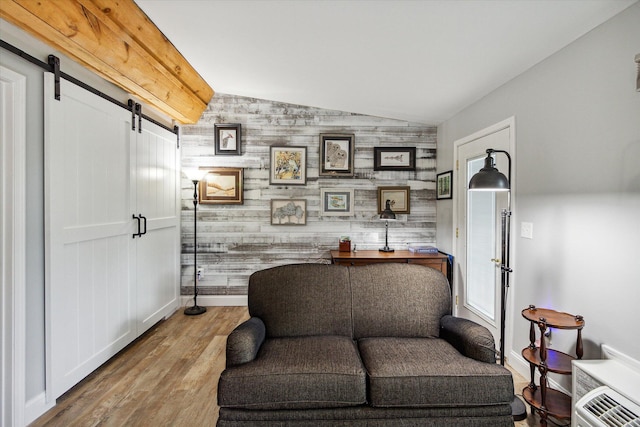 sitting room featuring light wood-type flooring, a barn door, vaulted ceiling, and wooden walls