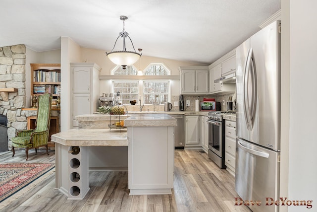 kitchen featuring a center island, hanging light fixtures, vaulted ceiling, and appliances with stainless steel finishes