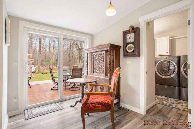 living area with washing machine and dryer, light wood-type flooring, and vaulted ceiling