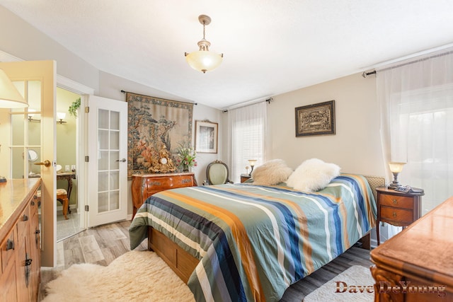 bedroom with vaulted ceiling and light hardwood / wood-style flooring