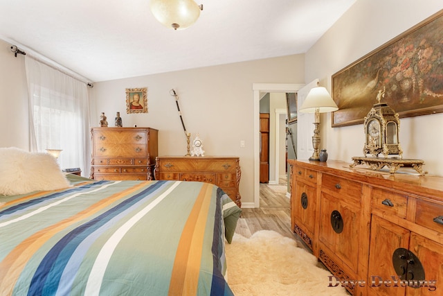 bedroom featuring light wood-type flooring and vaulted ceiling