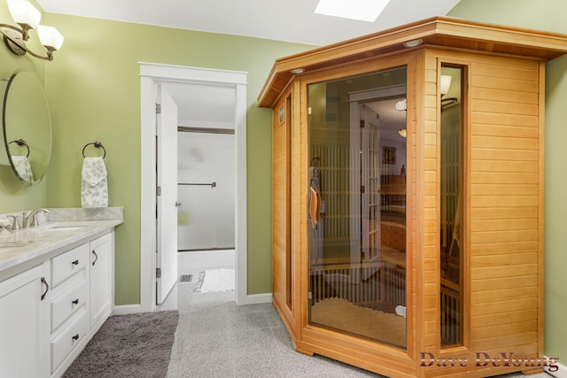 bathroom with vanity, walk in shower, and a skylight