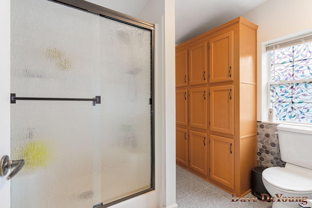 bathroom with tile patterned floors, toilet, and a shower with shower door