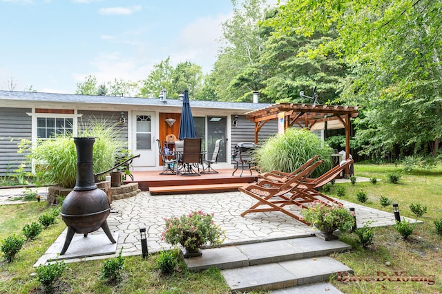 back of house with a pergola, a deck, and an outdoor fire pit