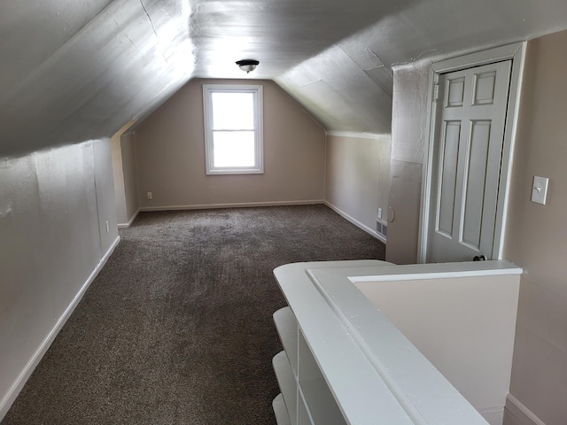 additional living space with lofted ceiling and dark colored carpet