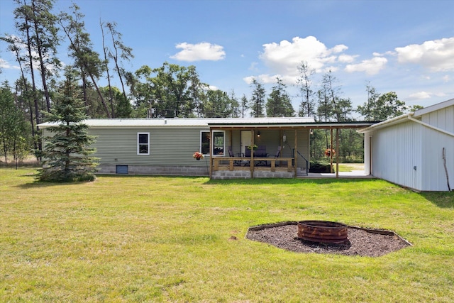 rear view of house with a lawn, covered porch, and an outdoor fire pit