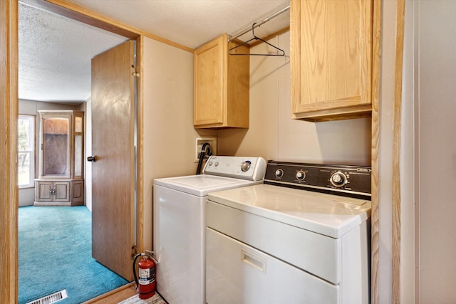 clothes washing area featuring cabinets, independent washer and dryer, a textured ceiling, and light carpet