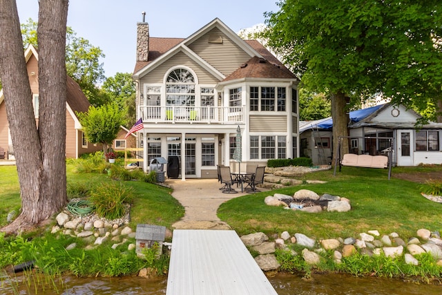 back of property featuring a patio area, a yard, and a water view