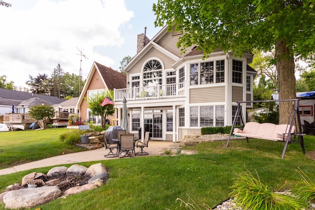 rear view of property with a patio area, a yard, and a balcony