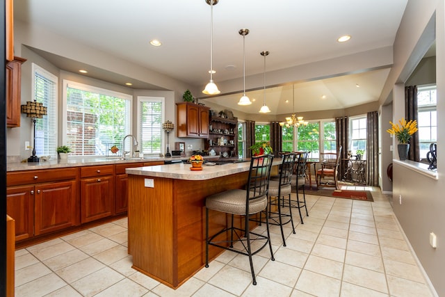 kitchen featuring light tile patterned floors, a center island, a notable chandelier, and sink