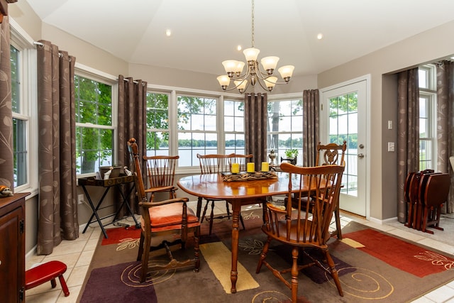 tiled dining room featuring a chandelier, a water view, and lofted ceiling