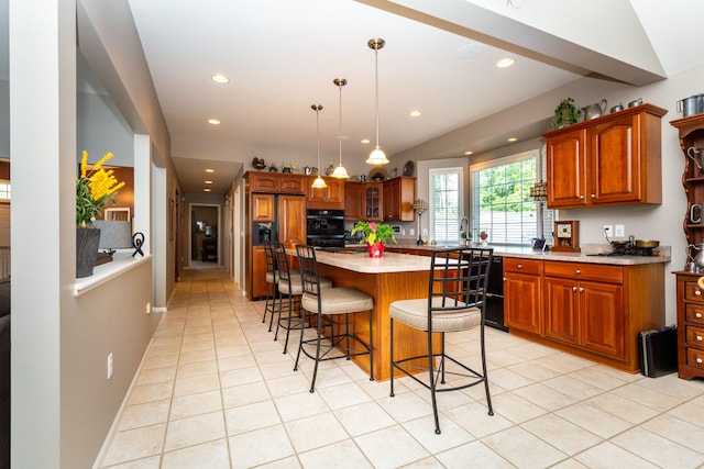 kitchen featuring a kitchen breakfast bar, vaulted ceiling, light tile patterned floors, a kitchen island, and hanging light fixtures