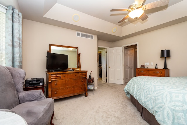 bedroom featuring light colored carpet, ceiling fan, and a tray ceiling