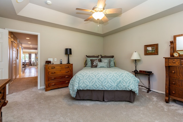 carpeted bedroom with a tray ceiling and ceiling fan