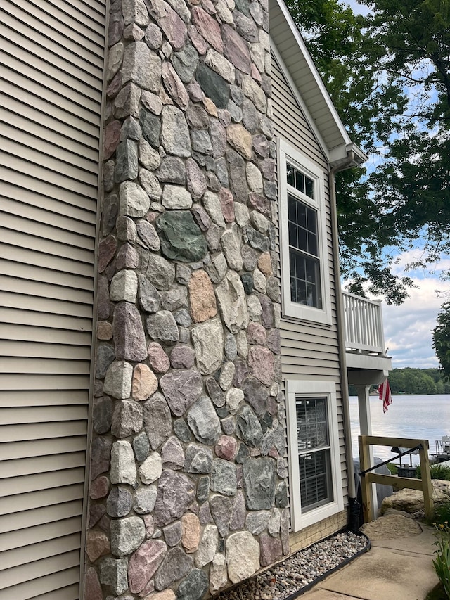 view of property exterior with a water view and a balcony