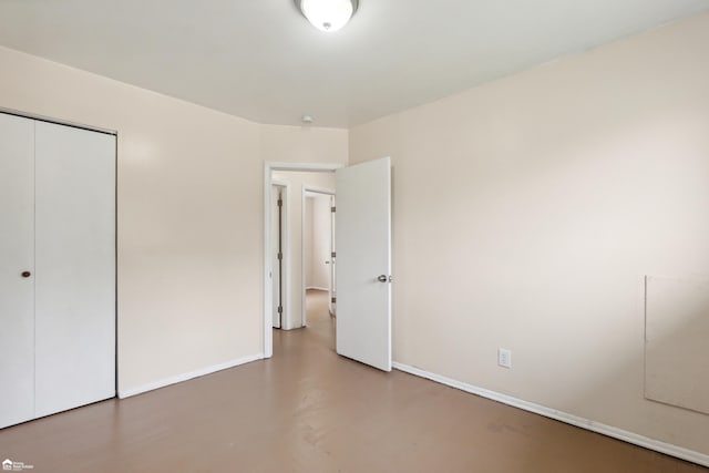 unfurnished bedroom featuring concrete floors and a closet