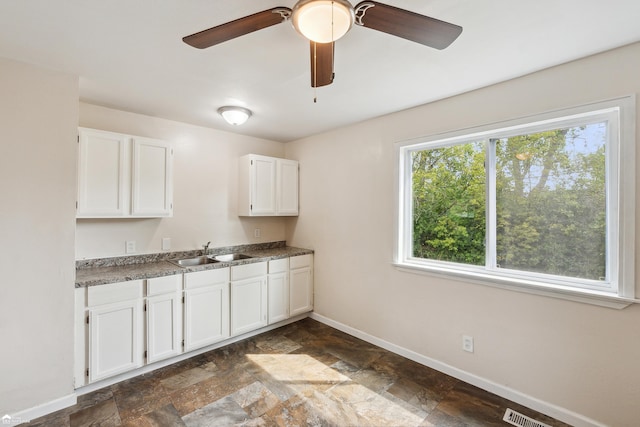 kitchen with white cabinetry, sink, and ceiling fan