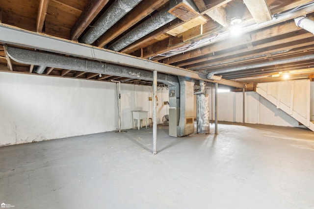 basement with heating unit, water heater, and sink