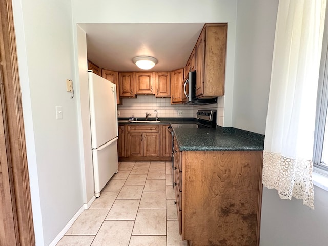 kitchen with backsplash, sink, light tile patterned floors, and white refrigerator