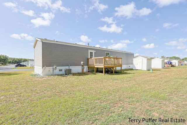 rear view of property with a shed, a deck, a yard, and central AC