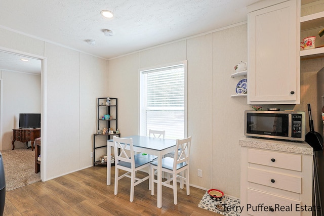 dining area featuring light hardwood / wood-style floors, a textured ceiling, and ornamental molding