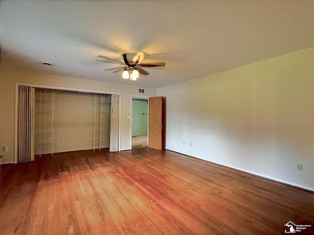 unfurnished bedroom featuring hardwood / wood-style floors, a closet, and ceiling fan