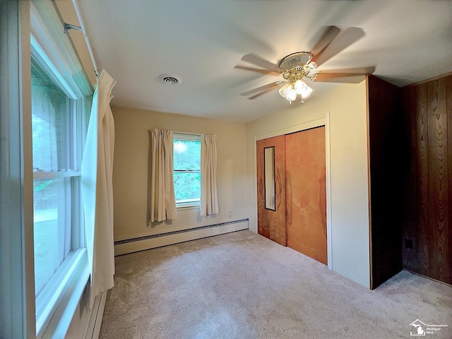 unfurnished bedroom with light carpet, a closet, a baseboard radiator, and ceiling fan