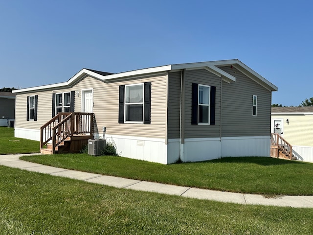 manufactured / mobile home featuring central air condition unit and a front lawn