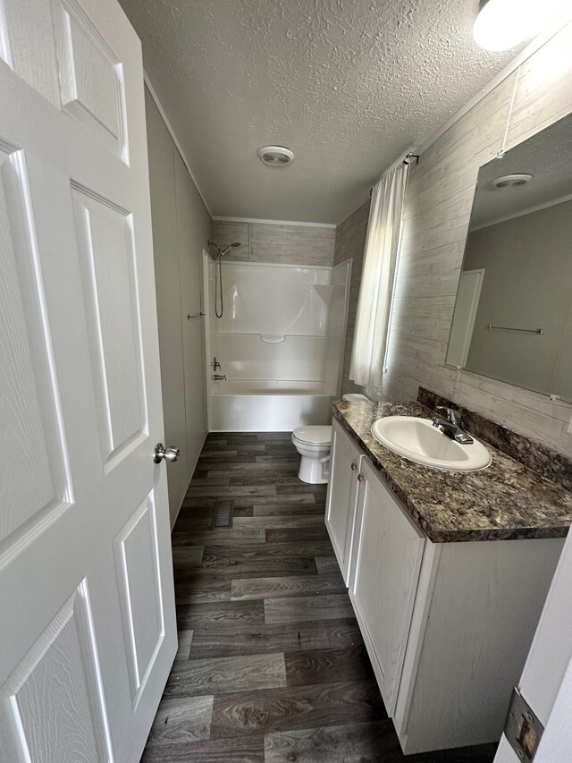 16678 Lakewood Dr, Holly, MI 48442 - bathroom with vanity, toilet, wood finished floors, a textured ceiling, and  shower combination