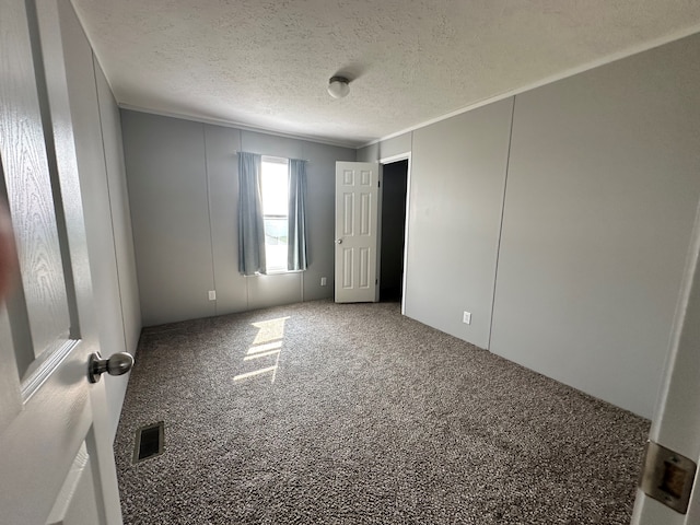 unfurnished room featuring a textured ceiling, carpet floors, and crown molding