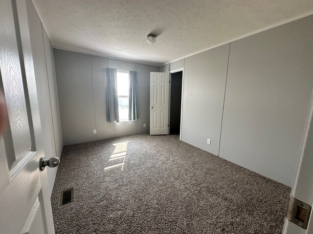 16678 Lakewood Dr, Holly, MI 48442 - unfurnished bedroom with carpet flooring, a textured ceiling, and ornamental molding