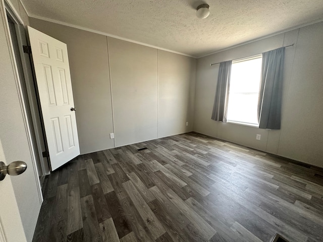 unfurnished room with a textured ceiling, dark hardwood / wood-style floors, and ornamental molding