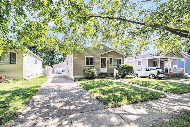 bungalow with a front lawn, an outdoor structure, and a garage