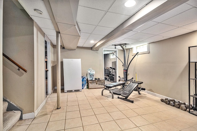 workout room with a paneled ceiling and light tile patterned floors