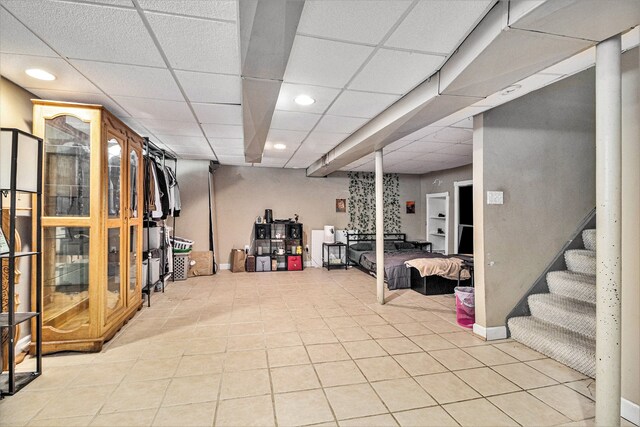 basement with light tile patterned floors and a drop ceiling