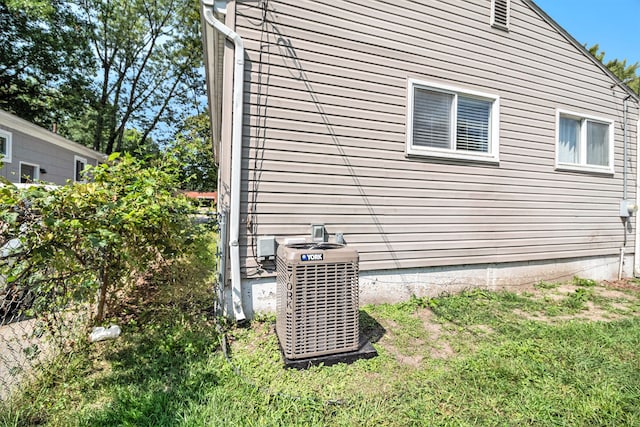 view of property exterior featuring central AC unit and a lawn