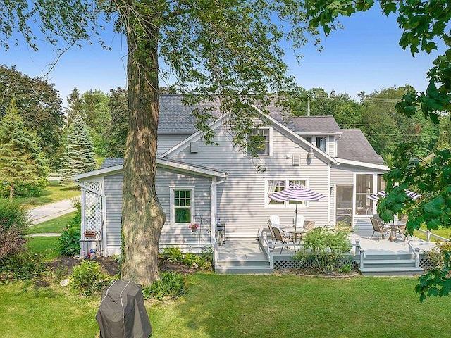 rear view of house with a wooden deck, a sunroom, and a yard