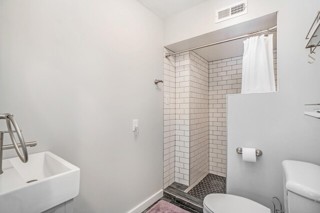 bathroom featuring toilet, sink, and a shower with shower curtain