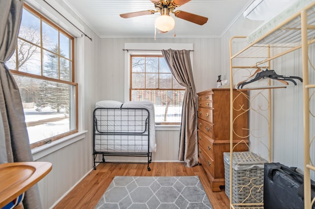 sitting room featuring ceiling fan, light hardwood / wood-style flooring, wood walls, and ornamental molding